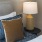 close up of a nightstand with a lamp next to a bed